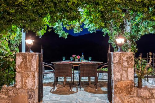 una mesa y sillas bajo un arco con luces en Stone Built Villa Galatia, Poolside & Perfect View, en Karés