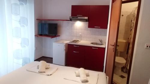 a small kitchen with red cabinets and a sink at Summerhouse Duće Omiš in Duće
