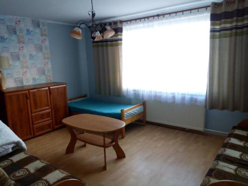 een woonkamer met een bank, een tafel en een raam bij Cichy Zakątek Junoszyno in Junoszyno