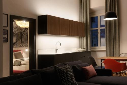 een woonkamer met een bank en een keuken met een bed bij Arte Apartments in Bolzano