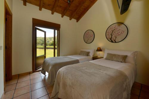 two beds in a room with a window at Piscina en Casa Rural con Encanto El Puentuco una de las casas mas valoradas de Cantabria in Villacarriedo