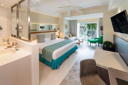 a hotel room with a bed and a living room at Catalonia Royal La Romana Adults Only - All Inclusive in Bayahibe