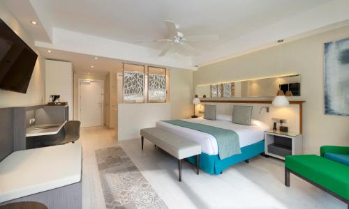 a bedroom with a bed and a tv and a couch at Catalonia Royal La Romana Adults Only - All Inclusive in Bayahibe