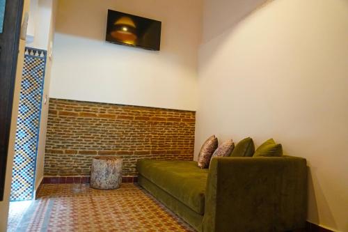 a living room with a green couch and a brick wall at Dar Fama in Tétouan