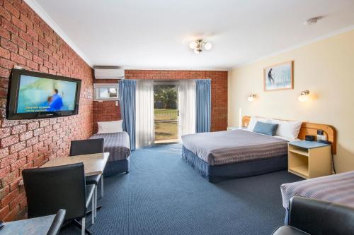 a hotel room with two beds and a tv at Torquay Tropicana Motel in Torquay