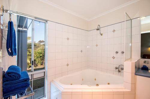 a bathroom with a tub, shower, and sink at Torquay Tropicana Motel in Torquay