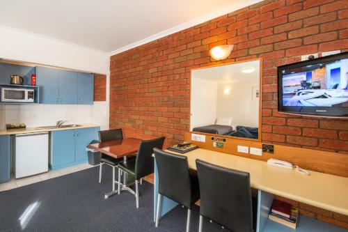 a kitchen with a tv and a table with chairs at Torquay Tropicana Motel in Torquay
