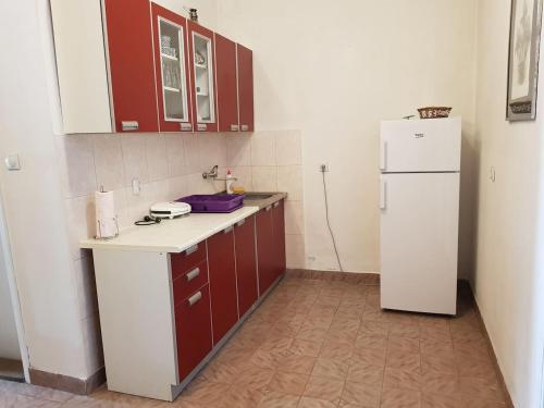 eine Küche mit roten Schränken und einem weißen Kühlschrank in der Unterkunft Kuca Pavle Trsteno in Budva