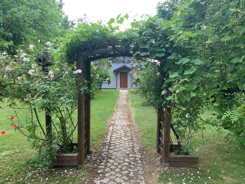 a garden with an arch with a path leading to a house at Apartamenty Podwarszawskie in Stara Wieś