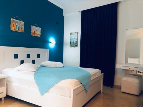 a bedroom with a white bed with a blue wall at Envi Hotel in Vlorë
