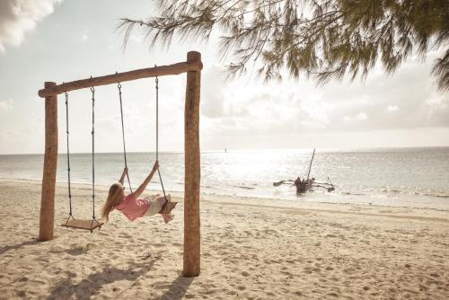 a girl swinging on a swing on the beach at Ifa Beach Resort in Jambiani