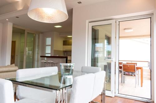 a dining room with a glass table and white chairs at House Mia in Ližnjan