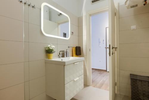 La salle de bains blanche est pourvue d'un lavabo et d'un miroir. dans l'établissement Apartments DREAM IN ARENA 1 Pula Center FREE PARKING, à Pula