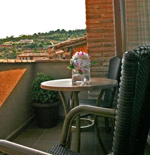 a table and chairs on a balcony with a vase of flowers at Hotel Castillo de Alquézar in Alquézar