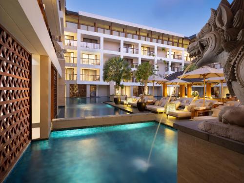 a hotel with a swimming pool in front of a building at The Bandha Hotel & Suites in Legian