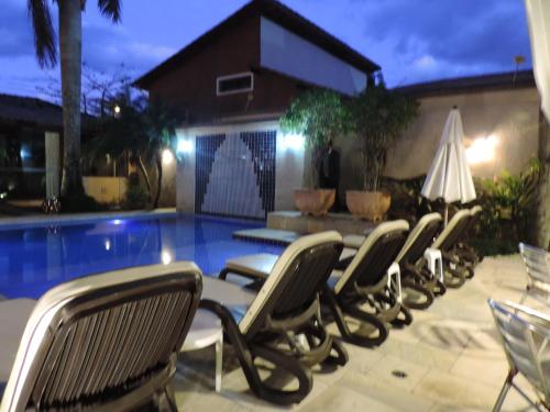 a row of chairs next to a pool at night at Hotel Costa Balena-Piscina Aquecida Coberta in Guarujá