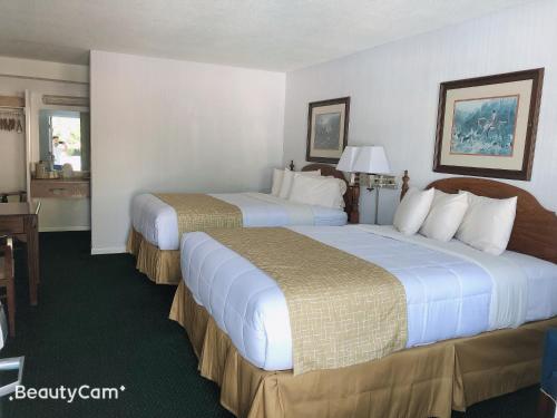 a hotel room with two beds and a desk at Travelodge by Wyndham Cape Cod Area in West Dennis