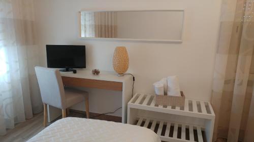 a bedroom with a desk with a television and a bed at Casinha D'Avó in Nazaré