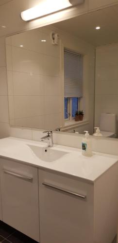 a white bathroom with a sink and a mirror at Pilan Lodge Lofoten in Vestpollen