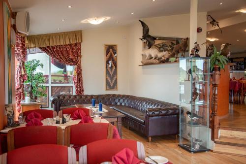 a restaurant with a leather couch and a table and chairs at Hotel Smyrlabjörg in Skálafell