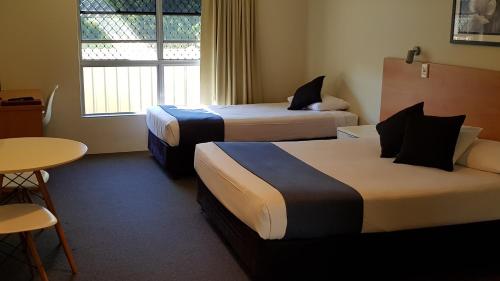 una camera d'albergo con due letti e un tavolo di Nambour Heights Motel a Nambour