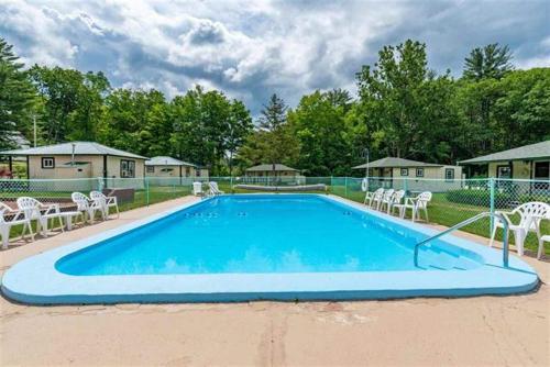 a large blue swimming pool with white chairs around it at Perry's Motel and Cottages in North Conway