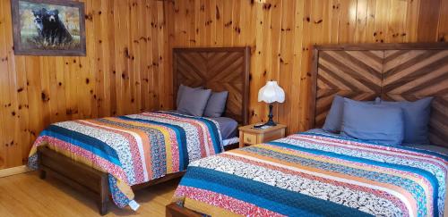 two beds in a room with wooden walls at Marshall's Creek Rest Motel in Gatlinburg