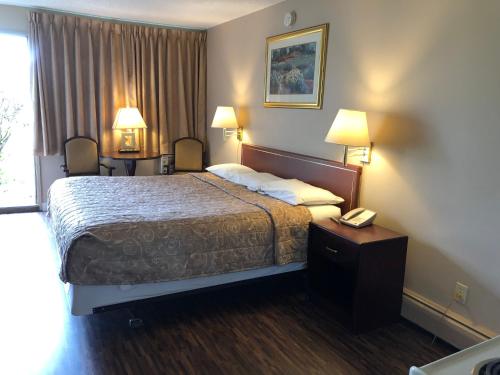 Habitación de hotel con cama y teléfono en Travellers Inn en Calgary