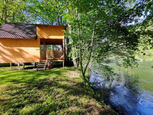 a log cabin with a deck next to a body of water at Riverland in Gornji Zvečaj