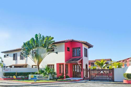 a red and white house with a fence at Residencial Mont Sinai - Tonziro in Porto Seguro