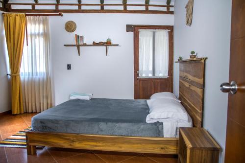 a bedroom with a large bed with a wooden headboard at Nibiru Hostel in Villa de Leyva