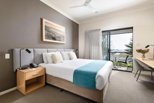 a bedroom with a large bed with a desk and a window at Quest Bunbury in Bunbury