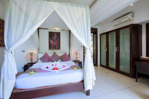 a bedroom with a white bed with a canopy at La Lagune in Laem Set Beach