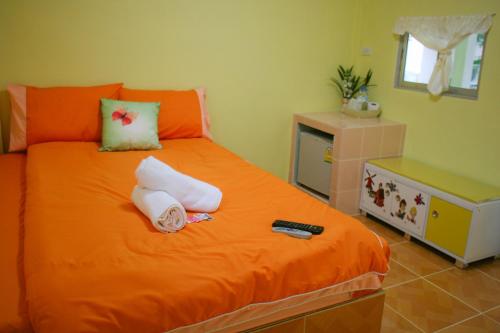 a bedroom with an orange bed with towels on it at Boathouse Resort Suanphung in Suan Phung