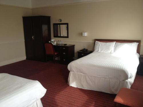 a hotel room with two beds and a desk at Best Western Hotel Hatfield in Lowestoft