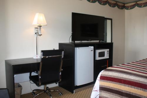 a hotel room with a desk with a computer and a tv at Chaparral Motor Inn in Burlington