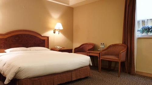 a hotel room with a bed and chairs and a window at Green World Flora Annex in Taipei