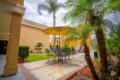 a patio with a table and chairs and a yellow umbrella at Howard Johnson by Wyndham Buena Park in Buena Park