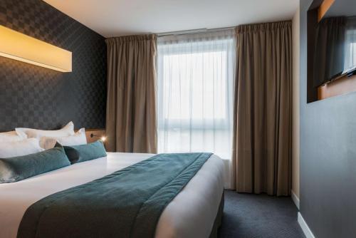 a hotel room with a large bed and a window at Best Western Plus Paris Saclay in Saclay