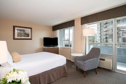 a hotel room with a bed and a chair and a window at Best Western Premier Chateau Granville Hotel & Suites & Conference Centre in Vancouver