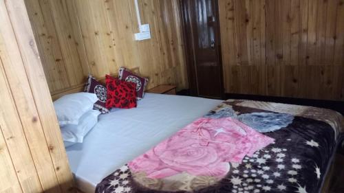 a large bed in a room with wooden walls at Vamoose Khaling in Pedong