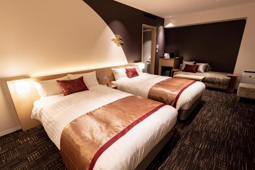 金沢市にあるホテルビスタ金沢のベッド2台とソファが備わるホテルルームです。