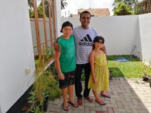 a man and two children standing next to a house at Ever Green Villa in Negombo