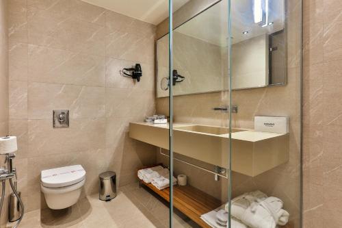 a bathroom with a toilet and a glass shower at Hotel Kalos in Budva
