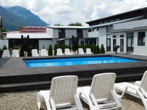 a group of white chairs and a swimming pool at Mountain Vista Suites in Zărneşti
