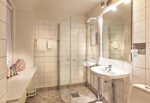 a white bathroom with a shower and a sink at Åkeshofs Slott in Stockholm