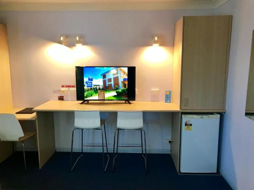 a room with a desk with two stools and a television at Cleveland Bay Air Motel in Cleveland