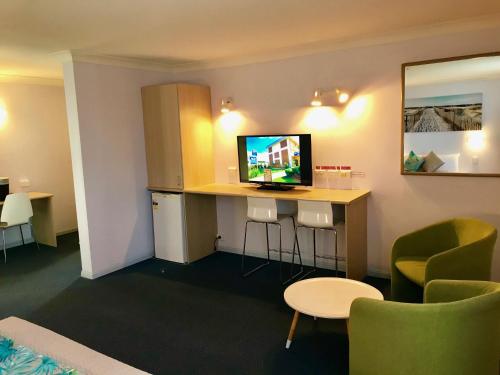 a room with a bar with a tv and chairs at Cleveland Bay Air Motel in Cleveland