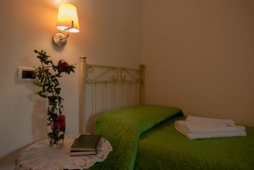 a small bedroom with a green bed with a table at Falesta in Casole dʼElsa