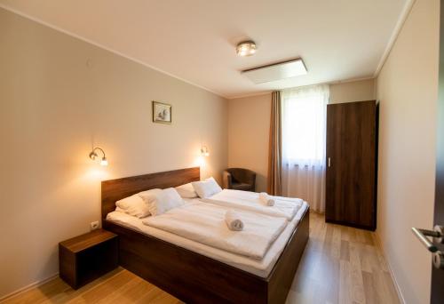 a bedroom with a large bed with white sheets at Dunazug Apartmanház in Dömös